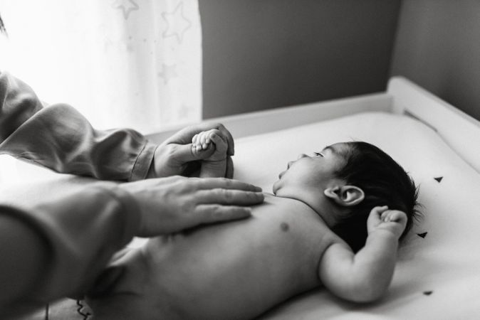 Crop mother playing with newborn baby boy