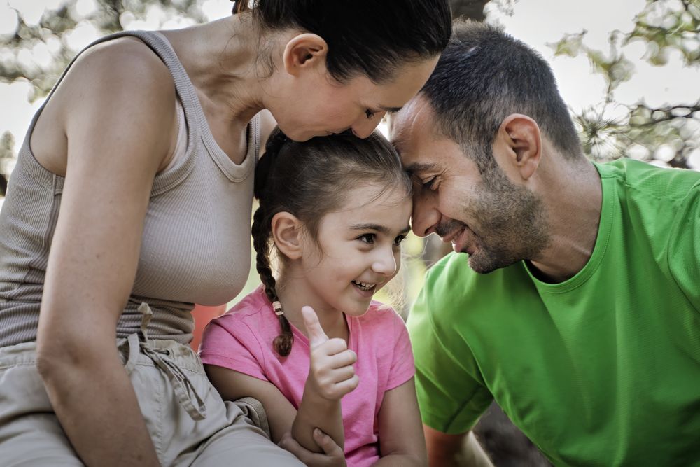 Happy family bonding moment in nature with smiling child showing thumbs up