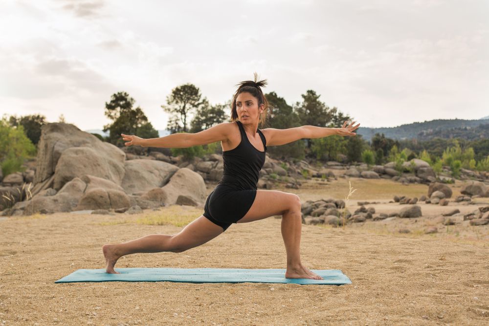 Woman practicing yoga outdoors near water