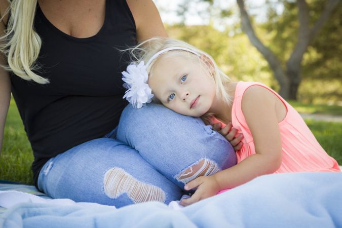 Young Girl Resting on Her Mommy's Lap At Park
