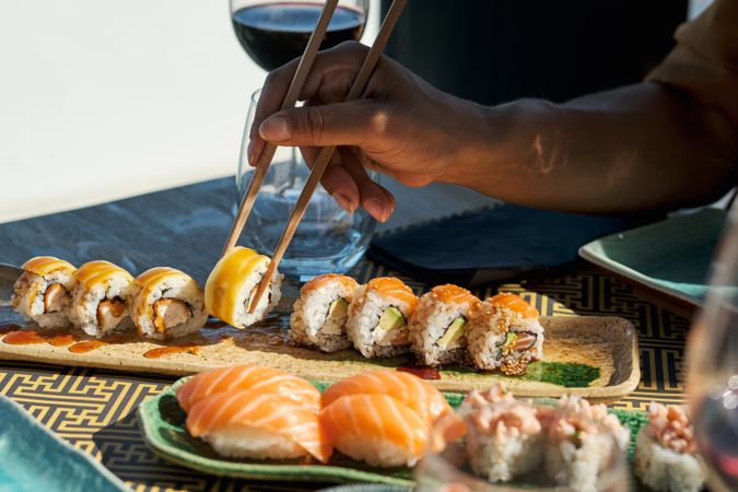 Faceless Person eating sushi and rolls