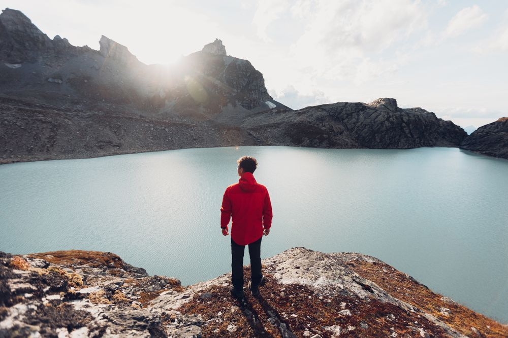 Back view of man standing on waterside of frozen lake during daytime