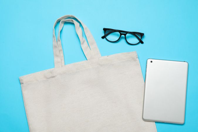 Eco bag, tablet and glasses on color background, space for text