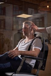 Crop barber cutting hair of male client
