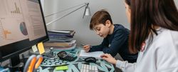 Mother helping her son with his homework while teleworking