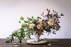 Composition of flowers and plants in vintage vase on board