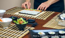 Chef placing avocado on rice as she makes fresh sushi rolls 47gKk4