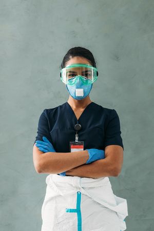 Portrait of Black female doctor with arms crossed in PPE gear, vertical