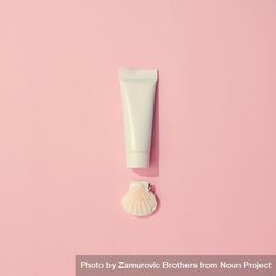 Sunscreen and shell on pastel pink background beY2Eb