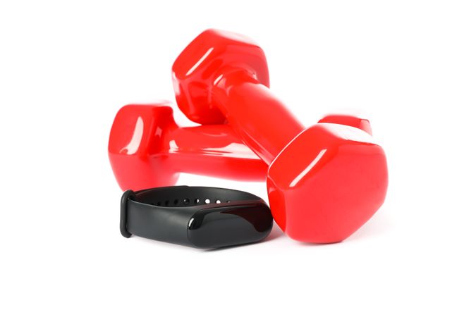 Red dumbbells and fitness tracker isolated on plain background