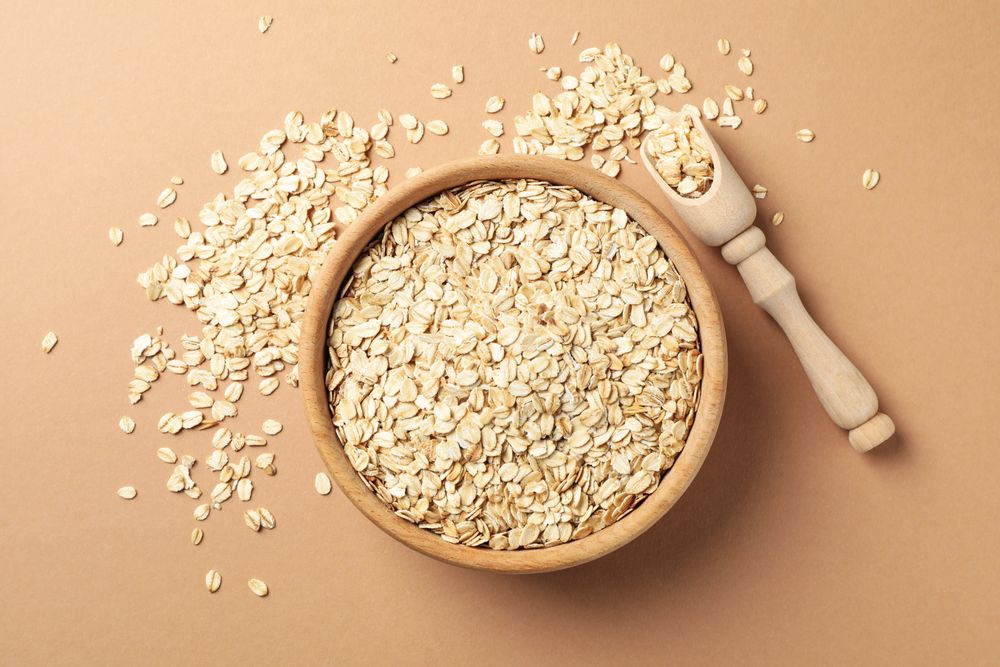 Bowl and scoop with oatmeal flakes on craft background