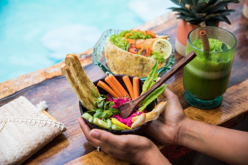 Black woman with fresh salad and shake on table