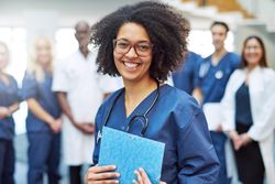Portrait of smiling Black woman in scrubs holding documents