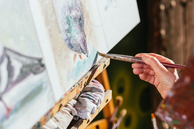 Anonymous woman painting on canvas in garden