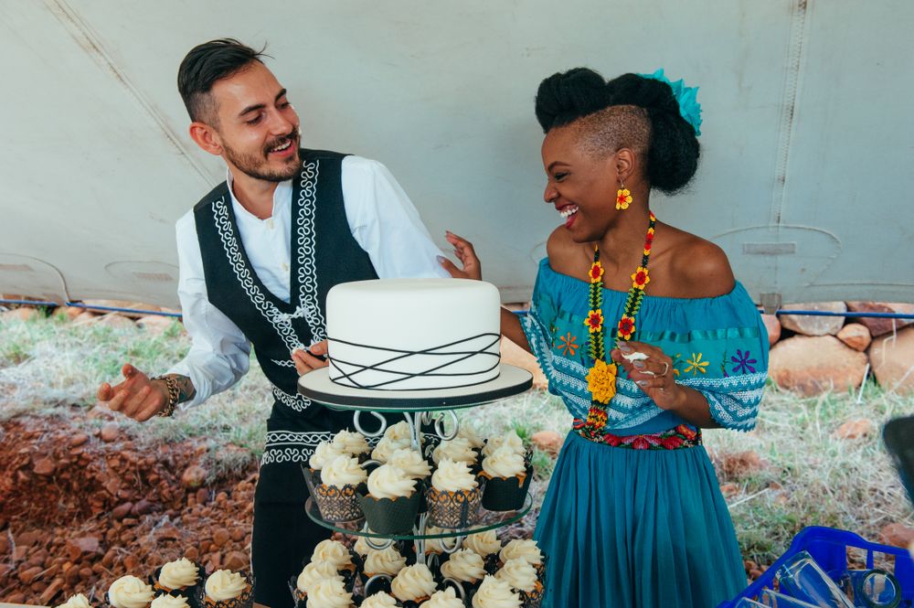 Bride and groom laughing behind wedding cake