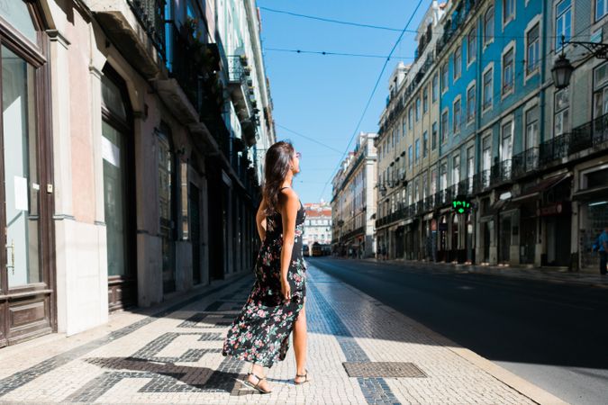 Carefree woman in sundress spinning on street