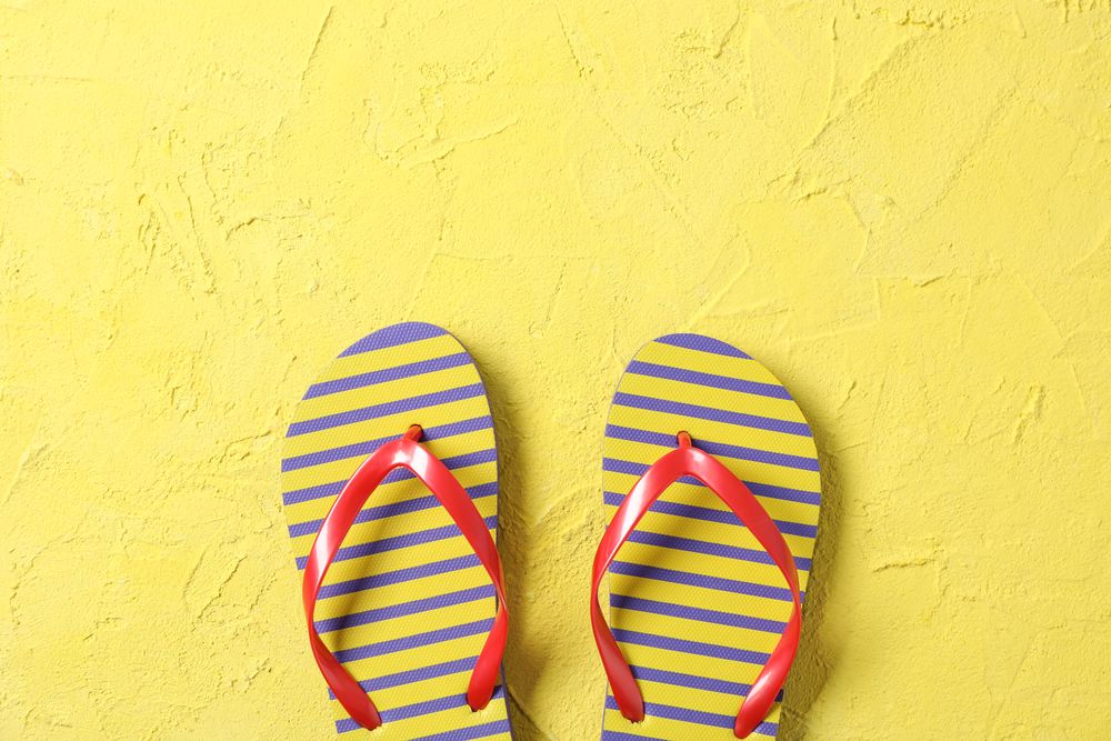 Flip flops on color background, space for text and top view. Summer vacation backdrop