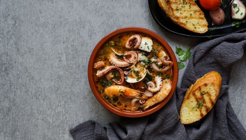 Soup of octopus and shrimps near toasts and spoon