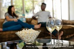 Popcorn and drinks with couple relaxing in background 5aXPG8