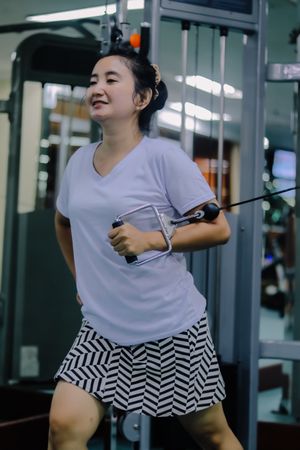 A woman at an indoor gym, actively engaged in an exercise routine using a cable machine.