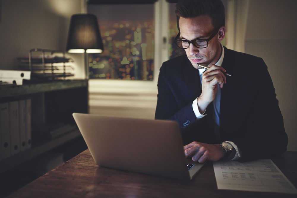 Contemplative man reading something on his laptop