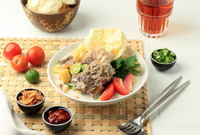 Soto betawi, bowl of Indonesian beef stew served on bamboo placemat
