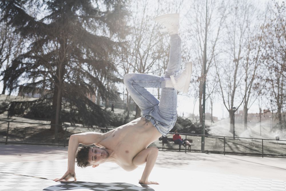 Shirtless man dancing break dance in park