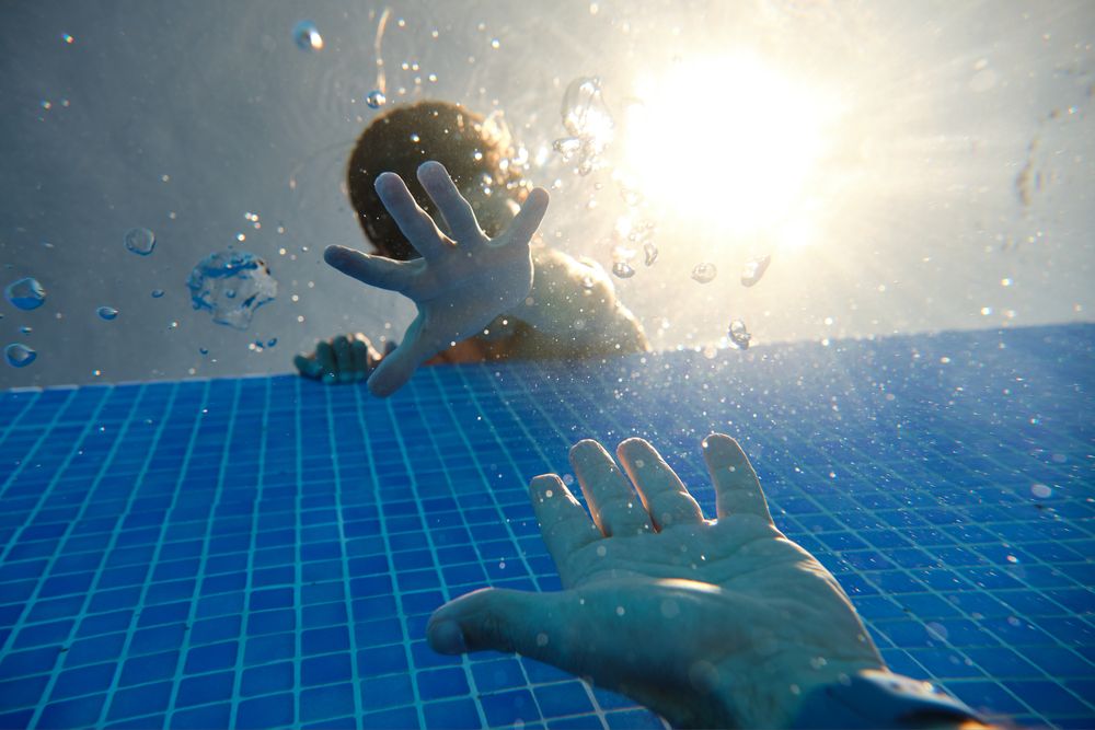 Unrecognizable boy and man reaching out hands in pool