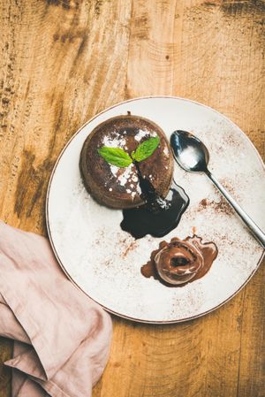 Top view of molten chocolate cake with mint garnish on plate and wooden table