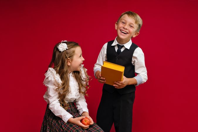 Happy preteen schoolchildren in uniform with books and apple