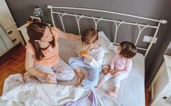 Top view of happy children having breakfast in bed with their mother on a relaxed morning
