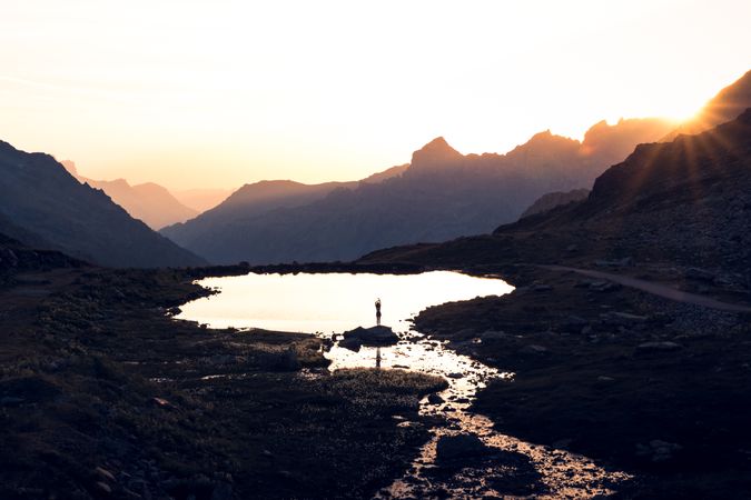 Person standing on shore and reflecting in water