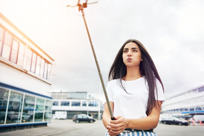 Woman puffing out her cheeks taking a selfie outside