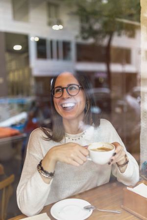 Young woman drinking hot beverage in cafe