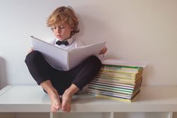 Focused boy in suit reading book