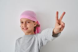 Cute boy showing two fingers gesture and smiling at camera