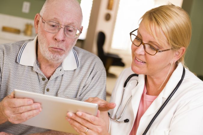 Doctor or Nurse Talking to Older Man with Touch Pad