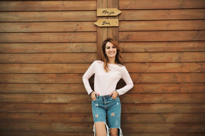 Woman leaning on wooden wall with two signs