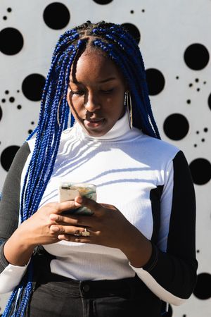Serious Black woman on mobile phone on street