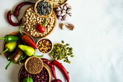 Top view of bowls of legumes and vegetables on counter