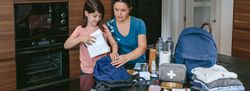 Mother preparing emergency backpack with her daughter