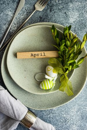 Easter concept with branch and green decorative eggs on grey ceramic plates