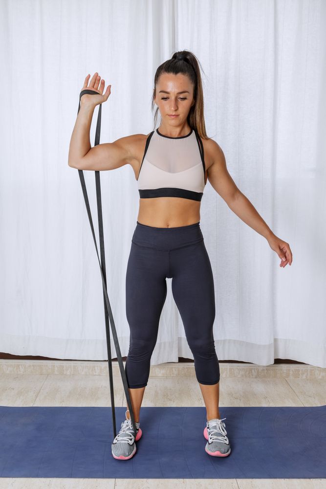 Young woman excising an arm using resistant rubber bands