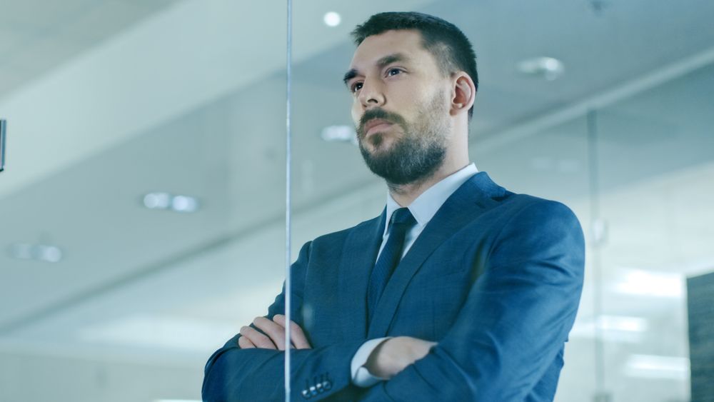 Suited Businessman Looks out of the Office Window.