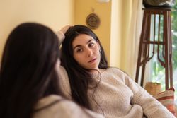 Young woman talking with worried face with her mother sitting on the sofa at home.