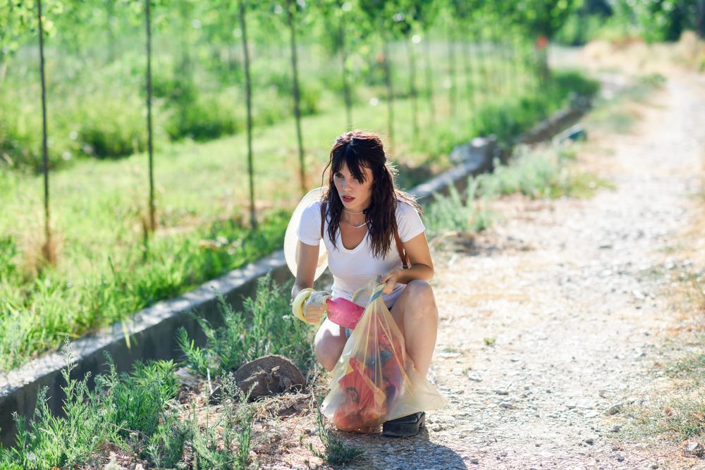 Woman cleaning up litter on footpath