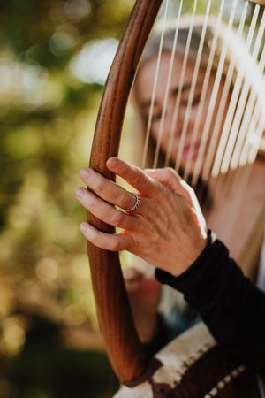 Sensual female musician playing lyre in garden