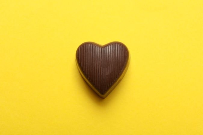 Chocolate candy in the heart form on yellow background