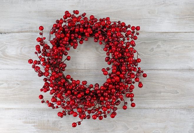 Red berry holiday wreath on old white wooden boards