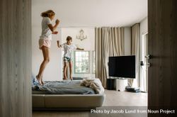 Mother and her little son jumping on bed 0WK9M0